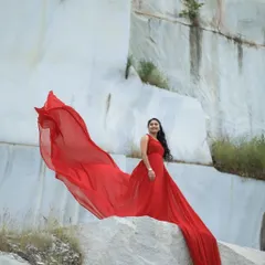 A solo portrait that commands attention. The fiery red train of this gown cascades down the rocks, creating a powerful and artistic statement for a portfolio or pre-wedding shoot.