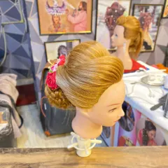A side view of the student's work, highlighting the smooth puff at the front and the secure placement of the bun.