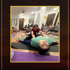 I am assisting a student with a reclining leg stretch. This kind of support helps to isolate the hamstring and prevent strain on the lower back.