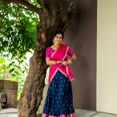 An outdoor portrait in a vibrant half-saree. The natural setting with the tree provides a lovely, rustic frame, while the bright colors of the outfit create a festive and joyful mood.