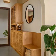 The foyer in 'Cover me in Sunshine' greets you with an arched entryway. The space combines style and function with an integrated shoe cabinet, mirror, and a comfortable seater bench.