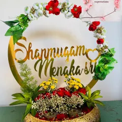 This is a personalized ring platter I designed for an engagement. It features the couple's names in a beautiful golden script, surrounded by fresh flowers, making the moment even more special.