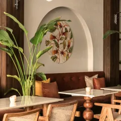 A closer look at the details in our Balinese-inspired cafe. The combination of large tropical plants, warm wood finishes, and custom artwork creates a layered and refreshing ambiance that blurs the line between the indoors and nature.