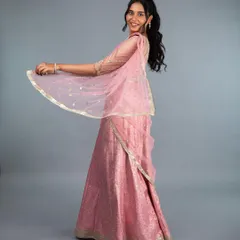 A full view of our stunning pink brocade lehenga. The lightweight fabric and elegant drape make it perfect for twirling on the dance floor at a sangeet or reception. The custom-fit blouse features delicate sleeve detailing, completing this graceful and timeless look.