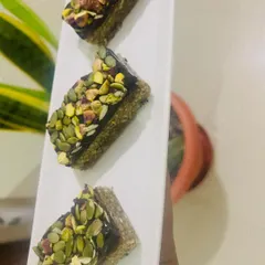 These are my Pumpkin Seed & Fig nutritional bars, topped with rich vegan chocolate and a generous sprinkle of pistachios. They are the ideal on-the-go snack, providing sustained energy without any refined sugar.