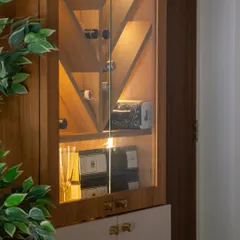 Storage can be beautiful. This close-up shows a thoughtfully styled bar cabinet, where the geometric wooden doors and warm interior lighting turn a functional piece into an elegant display.