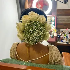 A classic bridal bun featuring a beautiful arrangement of white roses and baby's breath. This is a timeless and romantic choice for any bride.
