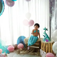 A magical mermaid-themed first birthday. We create an underwater wonderland in our studio with custom props, a knitted mermaid tail, and pastel balloons for a truly enchanting celebration.