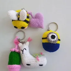 A collection of four of my whimsical crochet keychains. This set includes a bumblebee with a small heart, a character from the movie Minions, and a white llama paired with a tiny cactus, all made with colorful yarn.