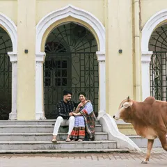 A candid, unscripted moment that makes hometown shoots so special. As the couple sat on the steps of a historic building in Sambalpur, a local resident, a cow, casually walked past, adding a touch of authentic, everyday life to their portrait.