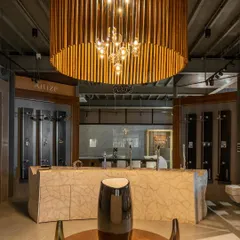 For this retail showroom in Shimoga, we took an industrial approach. The interior features a large, custom-built wooden chandelier and a marble-clad counter, creating a dramatic focal point that highlights the products on display.