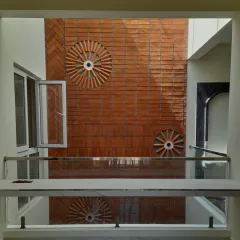 A straight-on view of the brick feature wall in the central courtyard. The circular patterns and herringbone layout create a dynamic texture that plays beautifully with the shadows cast by the skylight above.