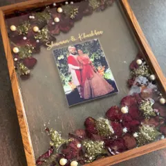 A premium varmala preservation piece in a deep wooden shadow box frame. This design includes the couple's photo and names, surrounded by their preserved wedding flowers.