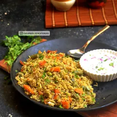 Our Vangibath is a flavorful and aromatic rice preparation from Karnataka, made with eggplant, a special spice powder, and fresh vegetables. It is served here with a cooling side of vegetable raita.