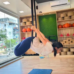 A student gracefully holds a pose in the aerial hammock, demonstrating the strength and flexibility gained through this practice.
