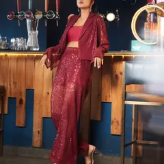 This red sequined two-piece set features wide-leg trousers and a matching jacket. It's a glamorous and modern take on a power suit, designed for parties and events.