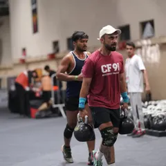 A farmer's carry with heavy kettlebells during a competition. This is a simple but brutal test of grip strength, core stability, and pure grit.
