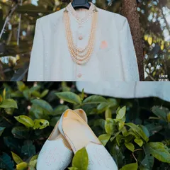 A detail shot of the groom's wedding attire, showcasing his elegant sherwani, pearl necklace, and traditional shoes (juttis).