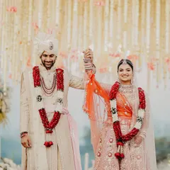 A moment of pure celebration after the Varmala. The couple raises their hands in joy, surrounded by family and a cascade of flowers, their smiles telling a story of a love that's officially begun.