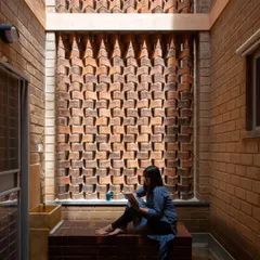 In this quiet courtyard nook, an intricately patterned brick screen, or jali, filters sunlight beautifully. This detail is more than just decoration; it’s a passive cooling strategy that allows for ventilation while providing privacy, demonstrating how traditional craftsmanship can create both comfort and art.