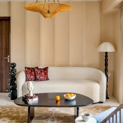 An eclectic living area from 'Project Lily' with a comfortable curved sofa, a unique black coffee table, and subtle striped wall texturing.