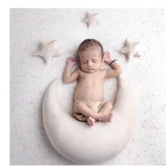 Over the moon for this little one. A simple and sweet celestial-themed shot with the baby sitting peacefully on a crescent moon prop, surrounded by soft stars.