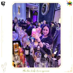 A guest poses with her beautifully crafted pink cocktail, with the bustling bar in the background. We love capturing these moments of pure enjoyment.