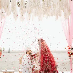 A shower of blessings. I love this perspective from under the mandap, as the groom kneels and flower petals rain down, creating a beautiful and emotional frame during the beach wedding ceremony.