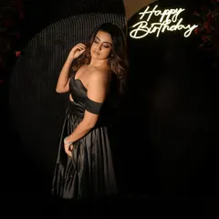 A full-length shot of the elegant adult birthday setup, showcasing the off-the-shoulder black gown against the dark, floral-accented backdrops.