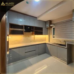 A sleek, modern kitchen in a grey high-gloss finish. The design includes under-cabinet lighting that illuminates the countertop and backsplash, creating a warm and functional workspace.