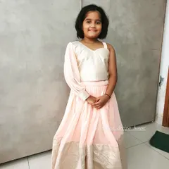 A still photograph of the charming pink and white kids' lehenga set. This shows the stylish one-shoulder top and the beautiful drape of the skirt, a perfect blend of modern design and traditional fabric.
