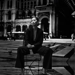 This cinematic black and white shot uses a projected European plaza to create a sense of place and mood. The composition makes the model look commanding and elegant amidst the grand architecture.