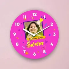 This clock is extra special because it features the child's own photo. The bright pink design is personalized with her name 'Swara' and the sweet message 'Be happy always'.