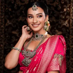 A beautiful smiling portrait showcasing a silver-finish oxidized set with green stones. The matching maang tikka and jhumkas complete this happy and radiant bridal look.