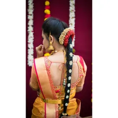 A detailed view of a traditional 'poola jada' with a modern twist. This long braid is decorated with jasmine, red flowers, and a traditional jadanagam ornament.
