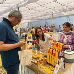 Here I am helping a customer, journalist Ravish Kumar, choose from the different treats at my stall. It brings me joy to see people appreciate the authentic taste of homemade food.