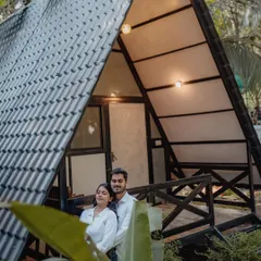 A stylish shot of a couple posing on the balcony of a unique A-frame resort cottage, perfect for a destination shoot.