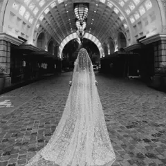 The timeless elegance of a bride's walk. This artistic, black and white portrait captures the quiet grace and anticipation of the moment, framed by dramatic architectural lines.