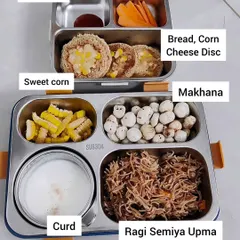 This lunchbox features ragi semiya upma, a nutritious alternative to regular upma. It's paired with makhana (fox nuts) for a crunchy snack, sweet corn, curd, and fun bread-corn-cheese discs with a side of ketchup.