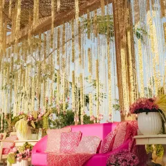 A vibrant pink sofa becomes the focal point under a bamboo pergola draped with jasmine garlands. This seating area from our 'Serene Vibes' Mehendi combines bold color with natural textures for a stunning effect.