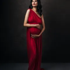 Another beautiful pose in the versatile red gown, showcasing its graceful lines and the serene beauty of the expecting mother.