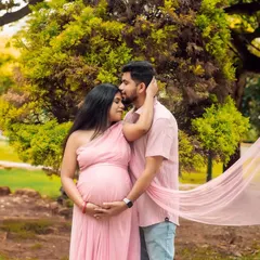 An intimate moment between expecting parents, captured in a beautiful park setting. The flowing pink fabric adds a touch of romance and softness to this outdoor maternity photo.