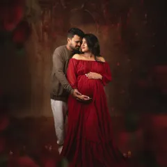 A romantic and dramatic studio portrait. The couple is surrounded by a cascade of red roses, with moody lighting that creates an intimate and passionate atmosphere.