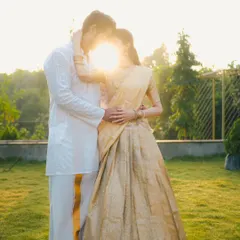 An artistic shot of a couple in traditional outfits, with the setting sun creating a beautiful flare between them. This silhouette-style portrait is both romantic and creative.