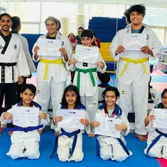 The pride of achievement. Here, a group of our students, both children and adults, proudly display their certificates after a successful Taekwondo belt promotion event, marking a significant step forward in their martial arts journey.