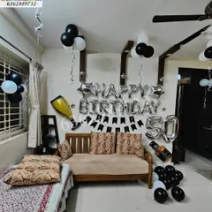 Here is a stylish 50th Golden Jubilee birthday celebrated at home. The decor features a classic black, white, and silver theme with 'Happy Birthday' and '50' letter and number foils, plus fun additions like a champagne bottle foil.