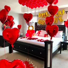 A grand proposal room setup filled with red heart-shaped foil balloons. The decor includes 'Will You Marry Me' foil balloons over the bed and a large engagement ring balloon arrangement.