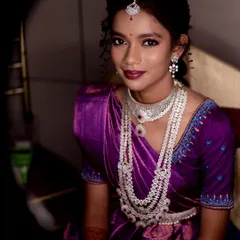 A stunning portrait of a woman in a purple saree, adorned with beautiful traditional jewelry. The lighting is set to create a dramatic, classic look.