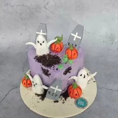 A spooky and fun Halloween cake featuring a graveyard scene. It has edible ghosts, pumpkins, and tombstones, with cookie crumble 'dirt' for a realistic effect.