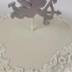 A close-up of the silver cupid topper and the delicate, hand-piped lace detail on the angel-themed cake. This level of detail adds a touch of vintage elegance to the design.